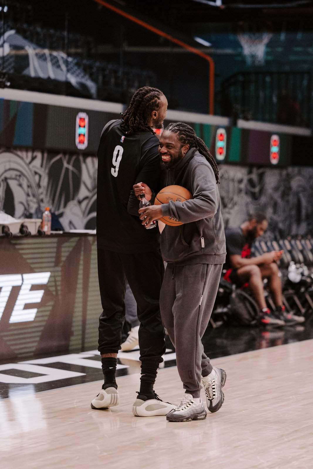Two people sharing a laugh courtside before a game